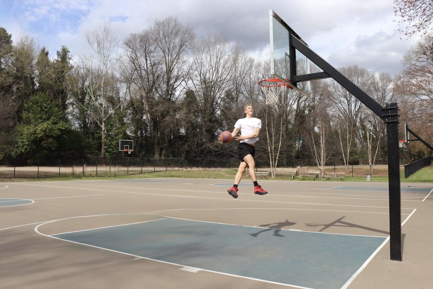 TRE WAY founder airborne with a basketball beside the hoop on an outdoor court